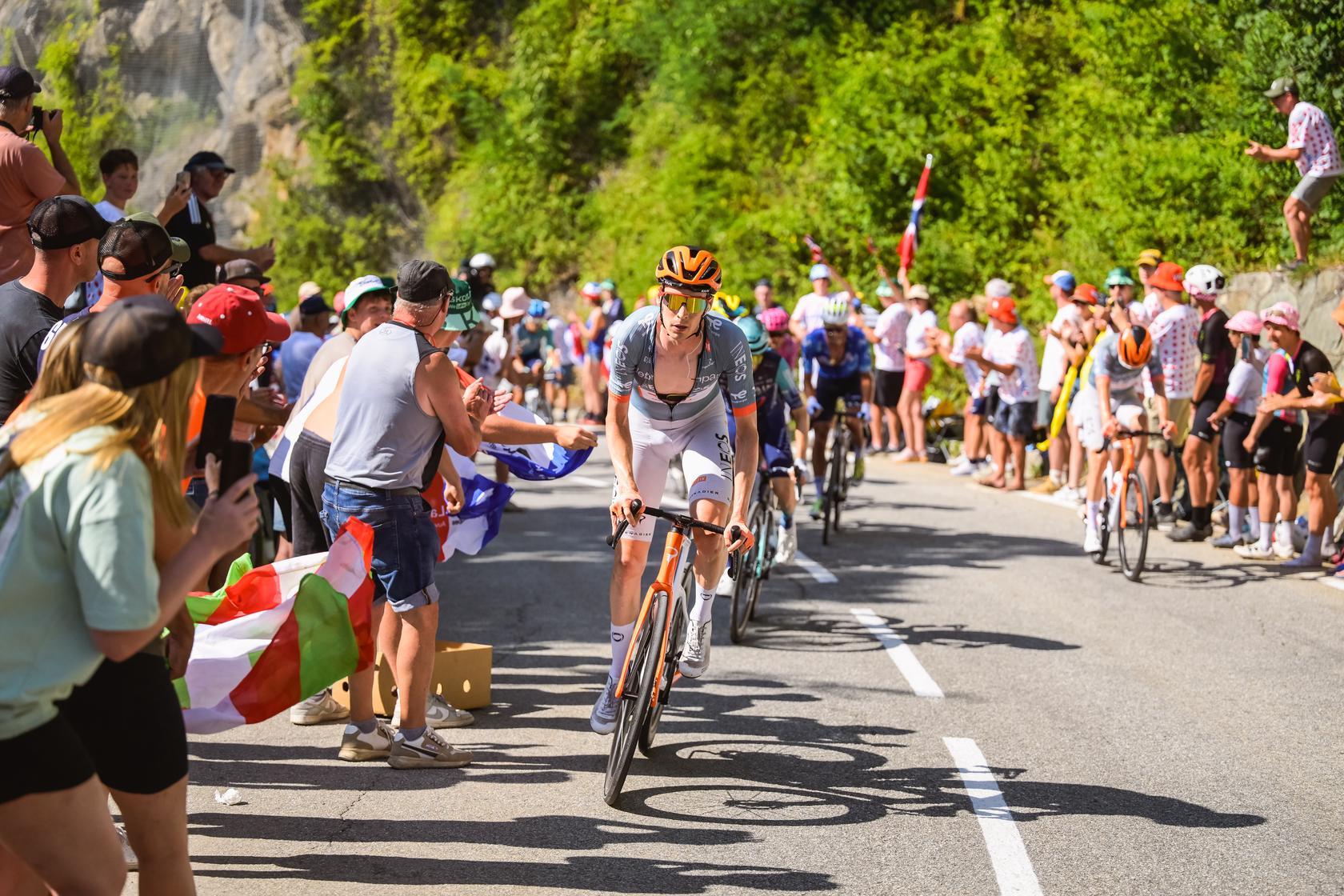 An INEOS Grenadiers rider leads a group of cyclists up a steep mountain climb during the Tour de France.