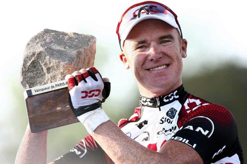 Stuart O'Grady celebrates his Paris-Roubaix 2007 victory with the iconic cobblestone trophy, smiling and wearing his Team CSC kit.