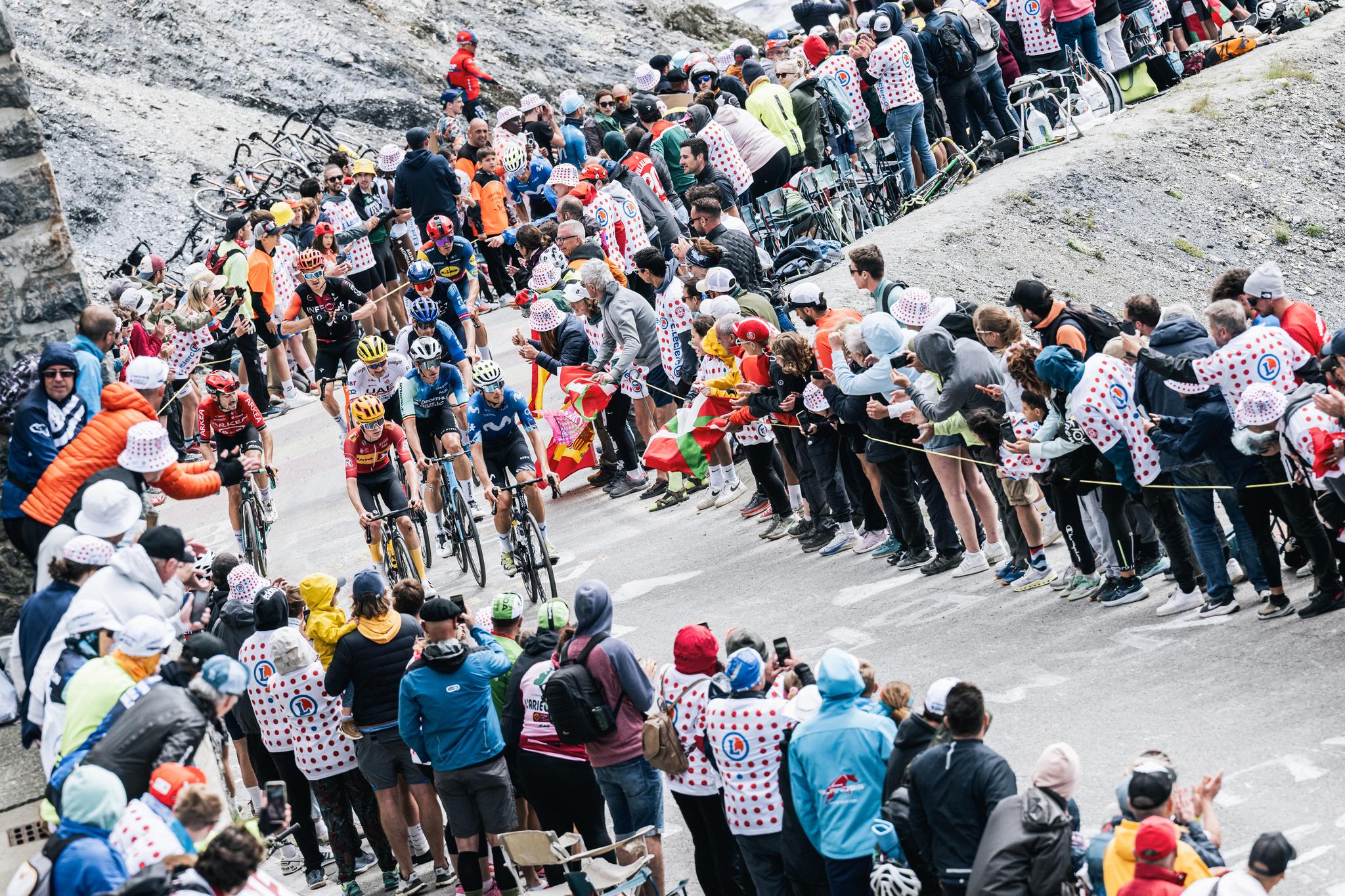 Riders climb a steep road lined with fans at the 2024 Tour de France.