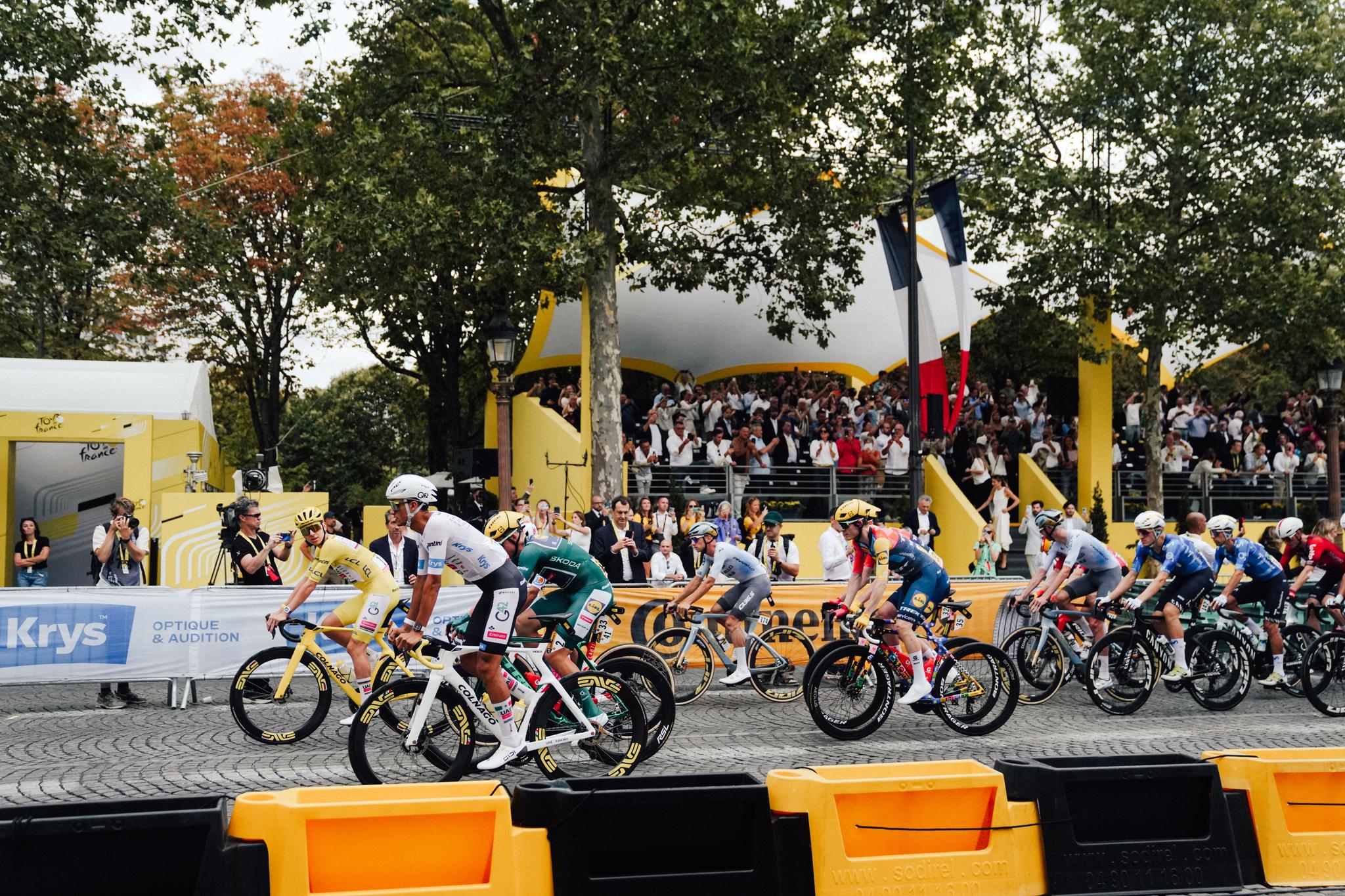 Tour de France 2026 Stage 21 on Champs-Élysées with yellow jersey rider leading a group of cyclists.