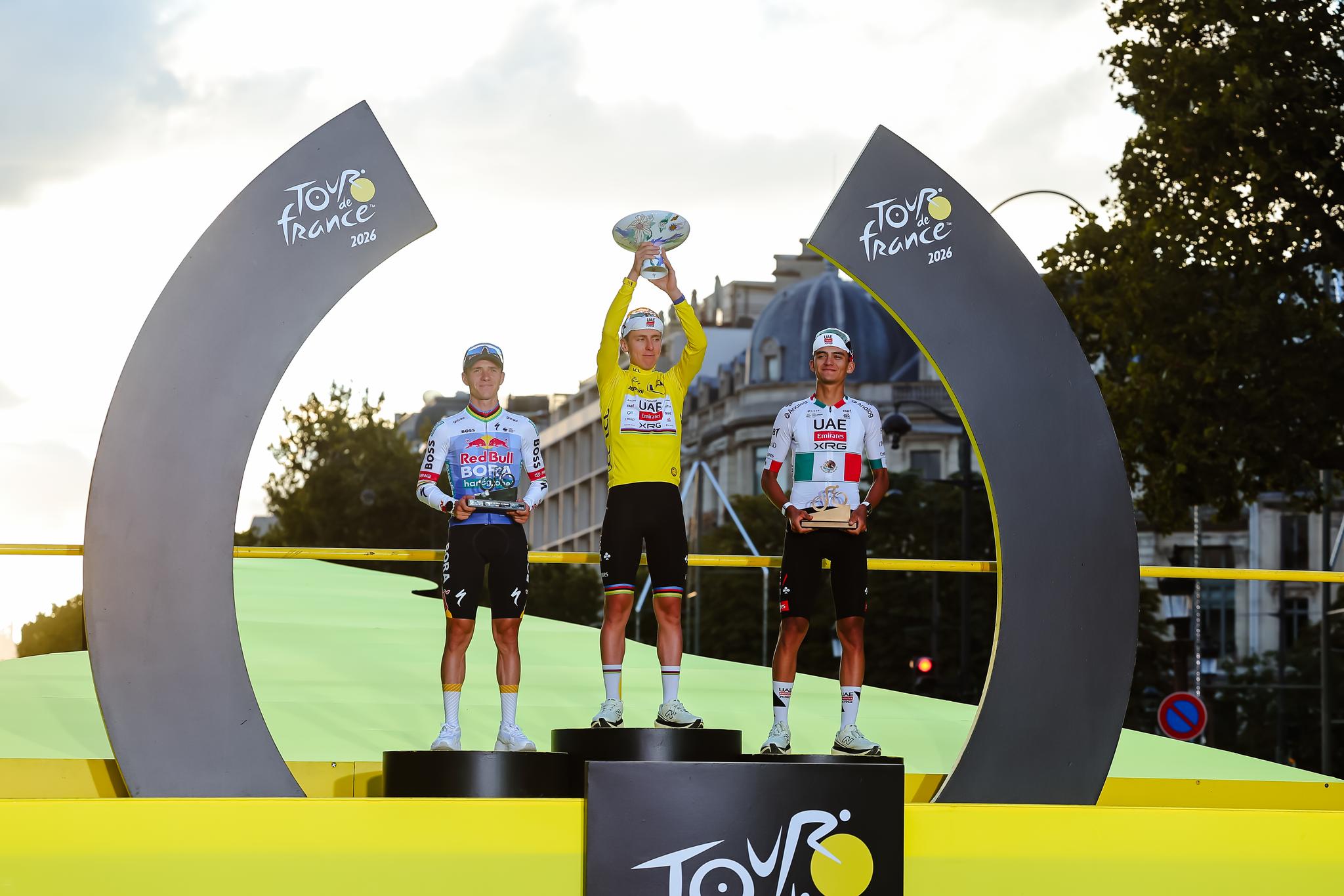 Tadej Pogačar (UAE Team Emirates) in yellow jersey celebrates Tour de France 2026 victory on the podium with Remco Evenepoel (BORA-hansgrohe) and Isaac Del Toro (UAE Team Emirates).