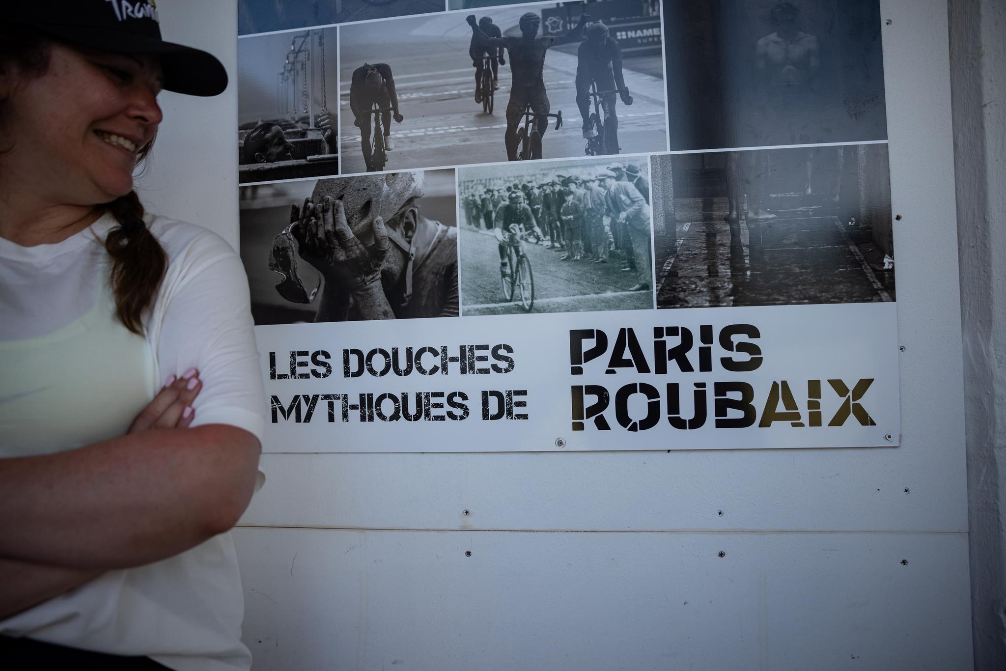 Woman smiles next to Paris-Roubaix poster