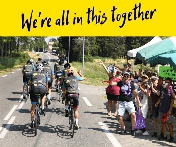 Cyclists riding on road, fans cheering