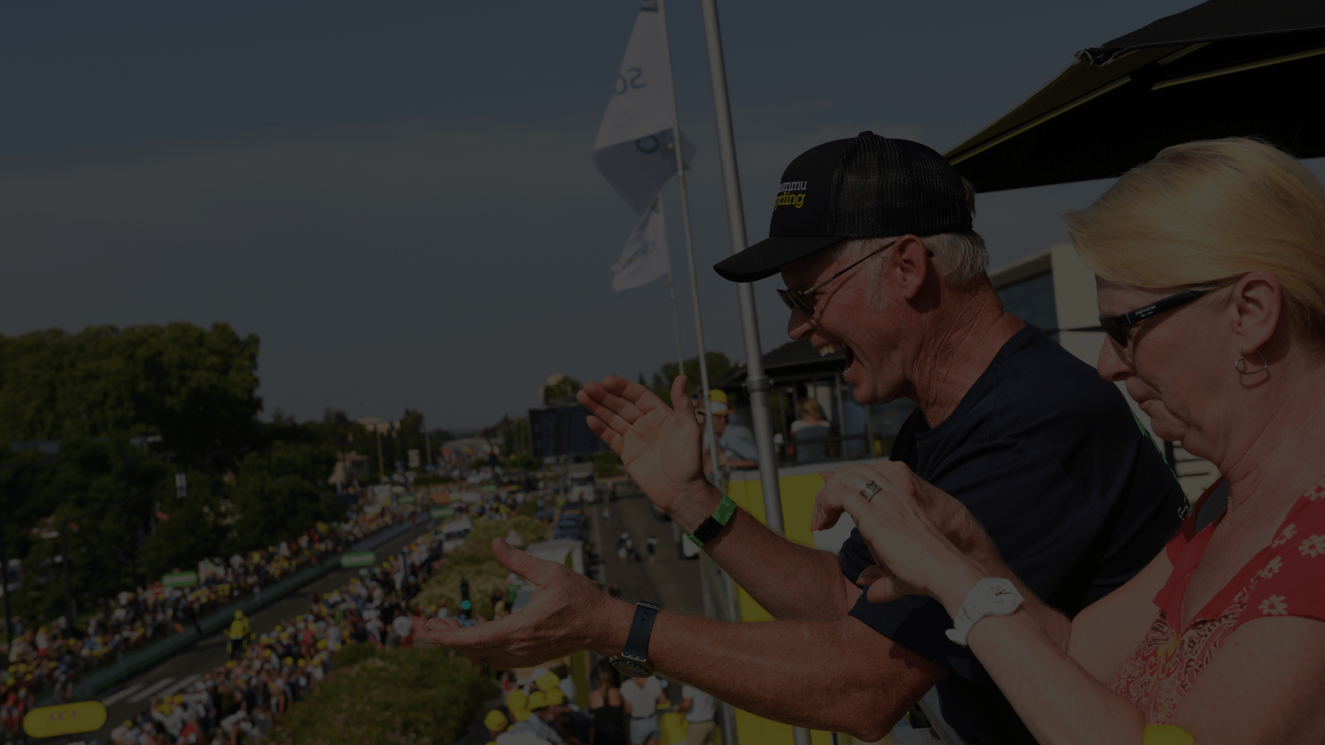 Enthusiastic cycling fans cheering from a balcony.