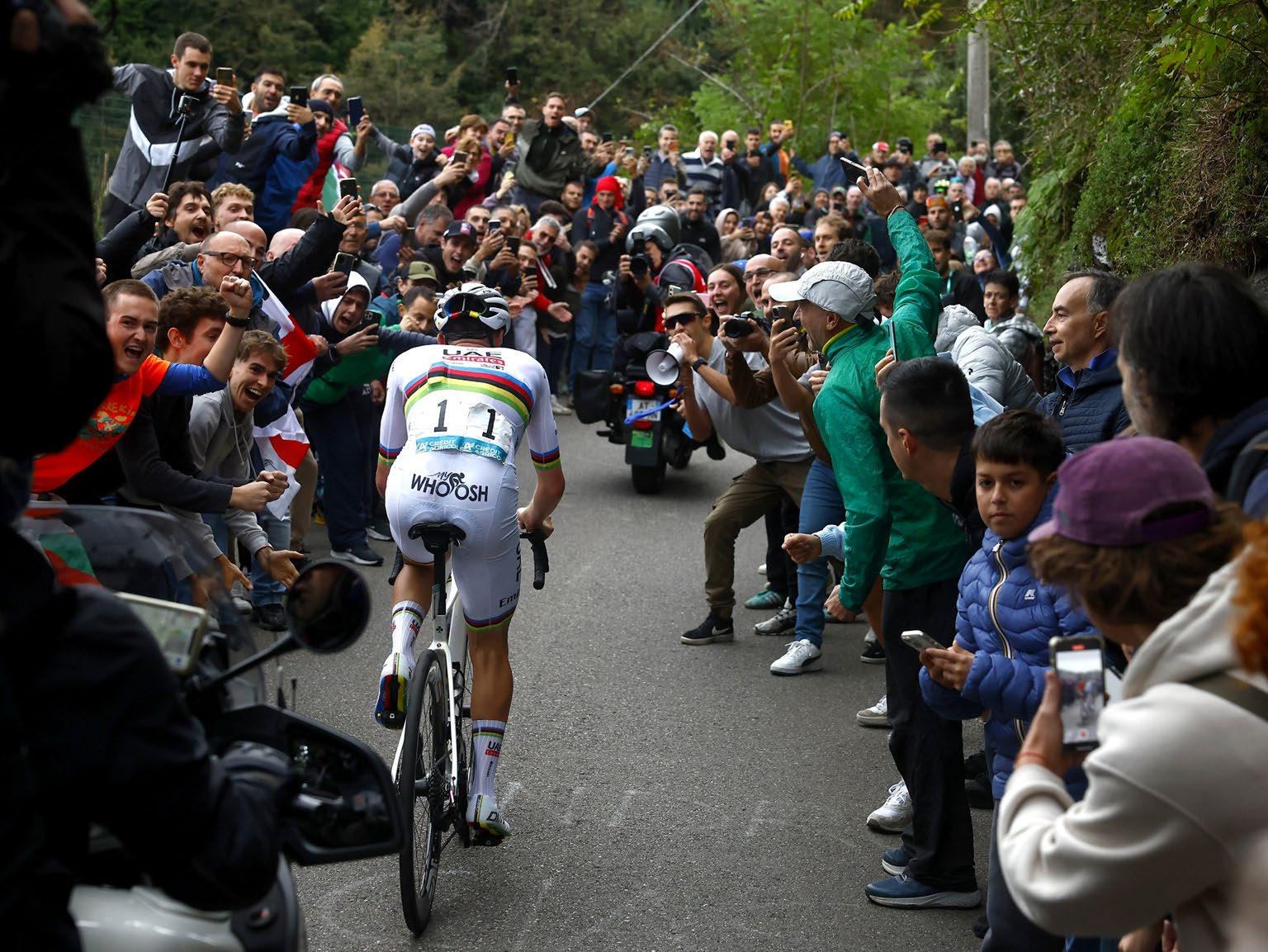 Tadej Pogačar in the rainbow jersey climbs alone through a wall of fans at Il Lombardia