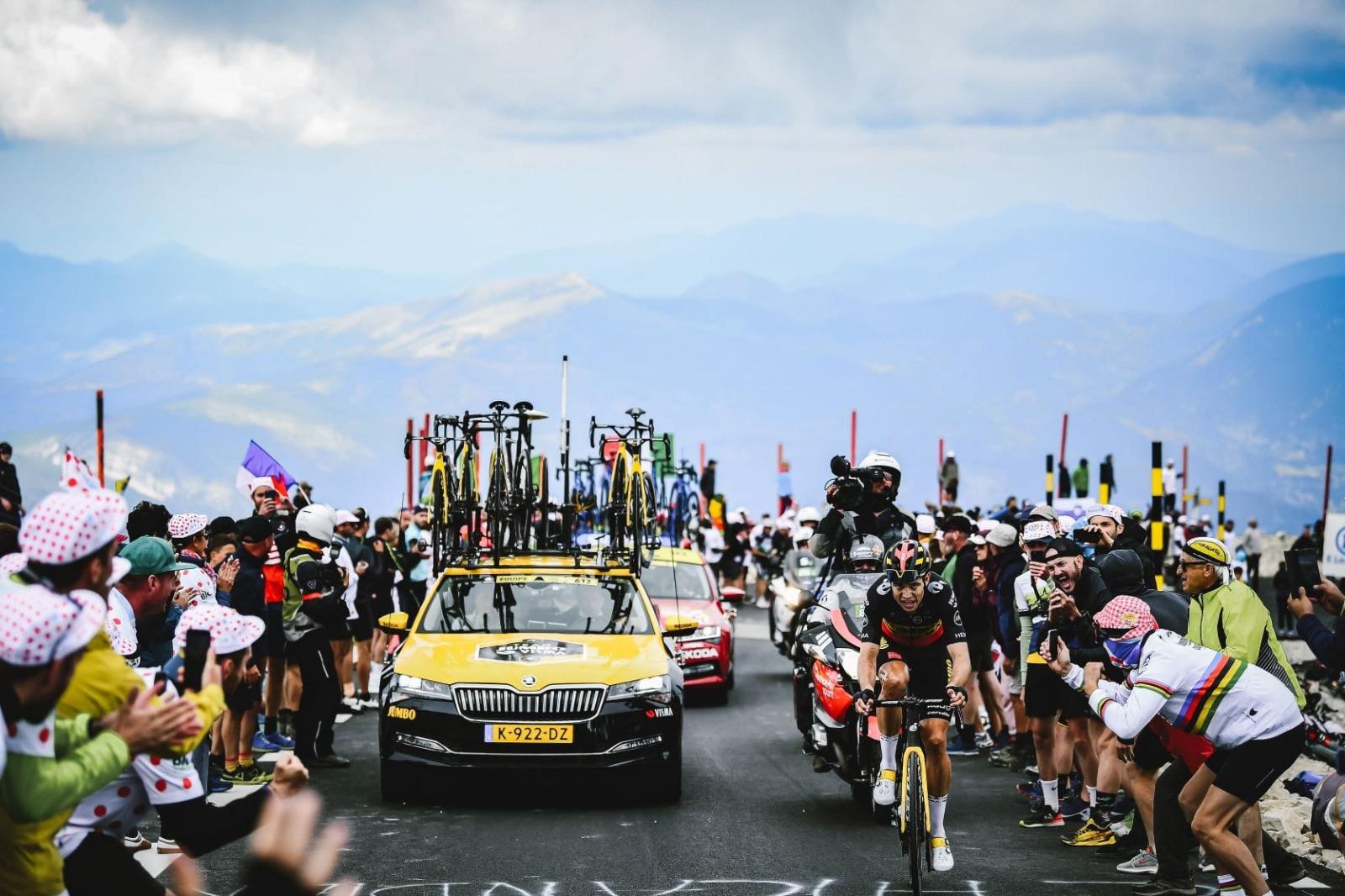 Cyclist racing with team car on mountain climb, Tour de France